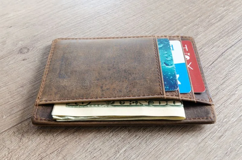 A leather wallet holding cash and payment cards