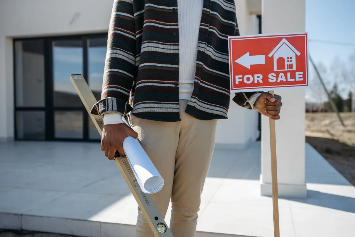 An agent holding a For Sale sign in front of a property